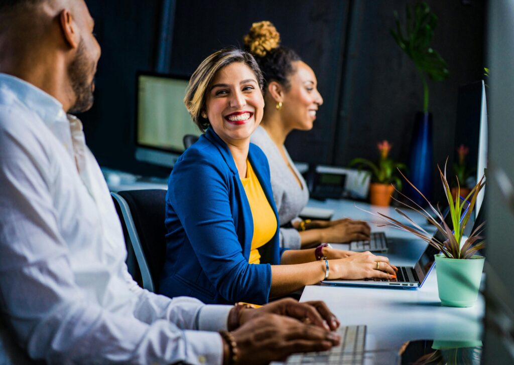 Three cheerful employees working at laptops.