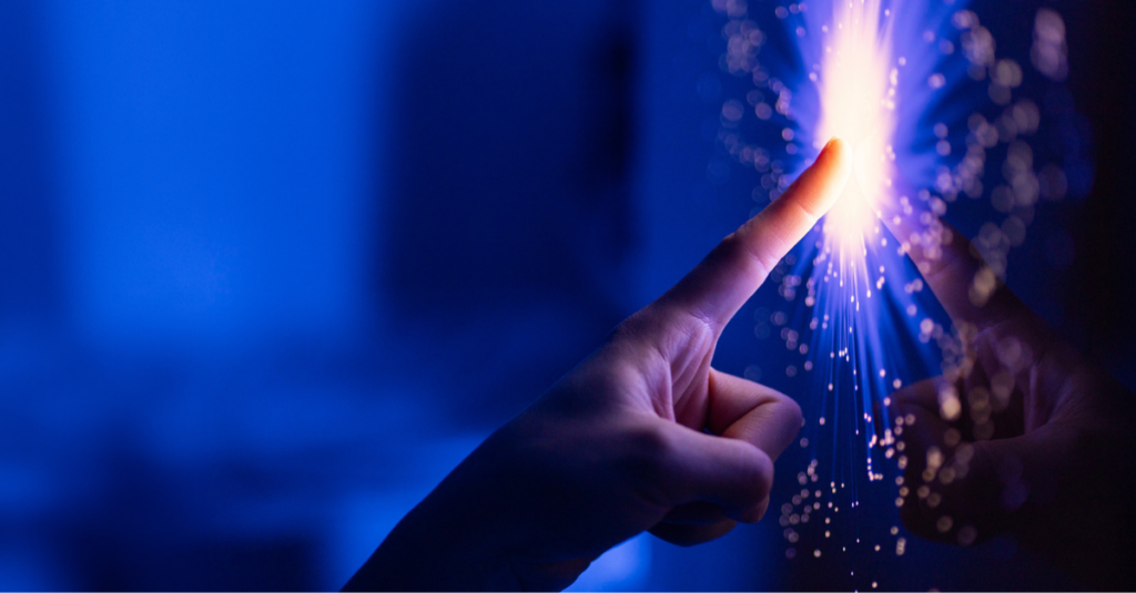 Finger touching a screen and creating a sparkling effect against a blue background